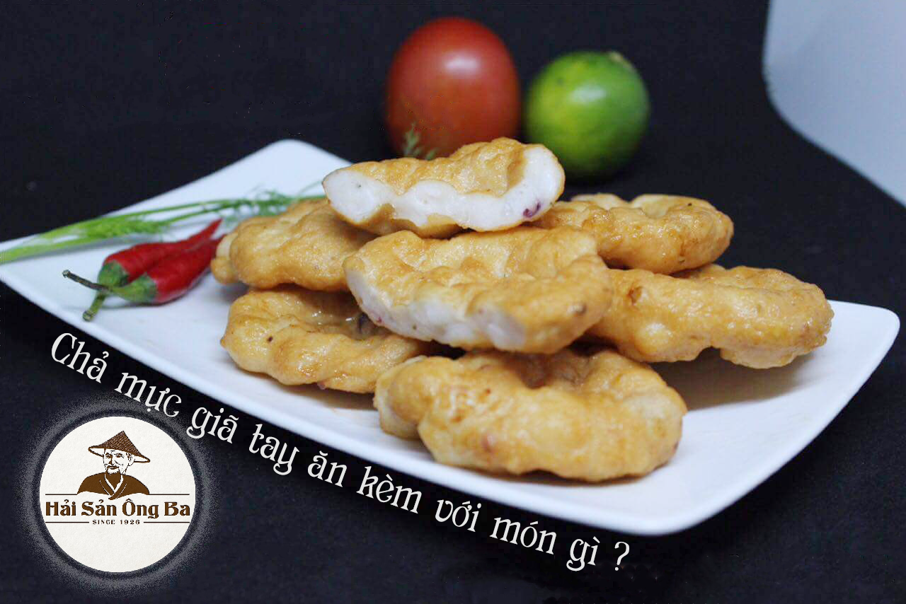 đĩa chả mực giã tay trên bàn màu đen, quả ớt trên cái đĩa, quả chanh và quả cà chua trên bàn